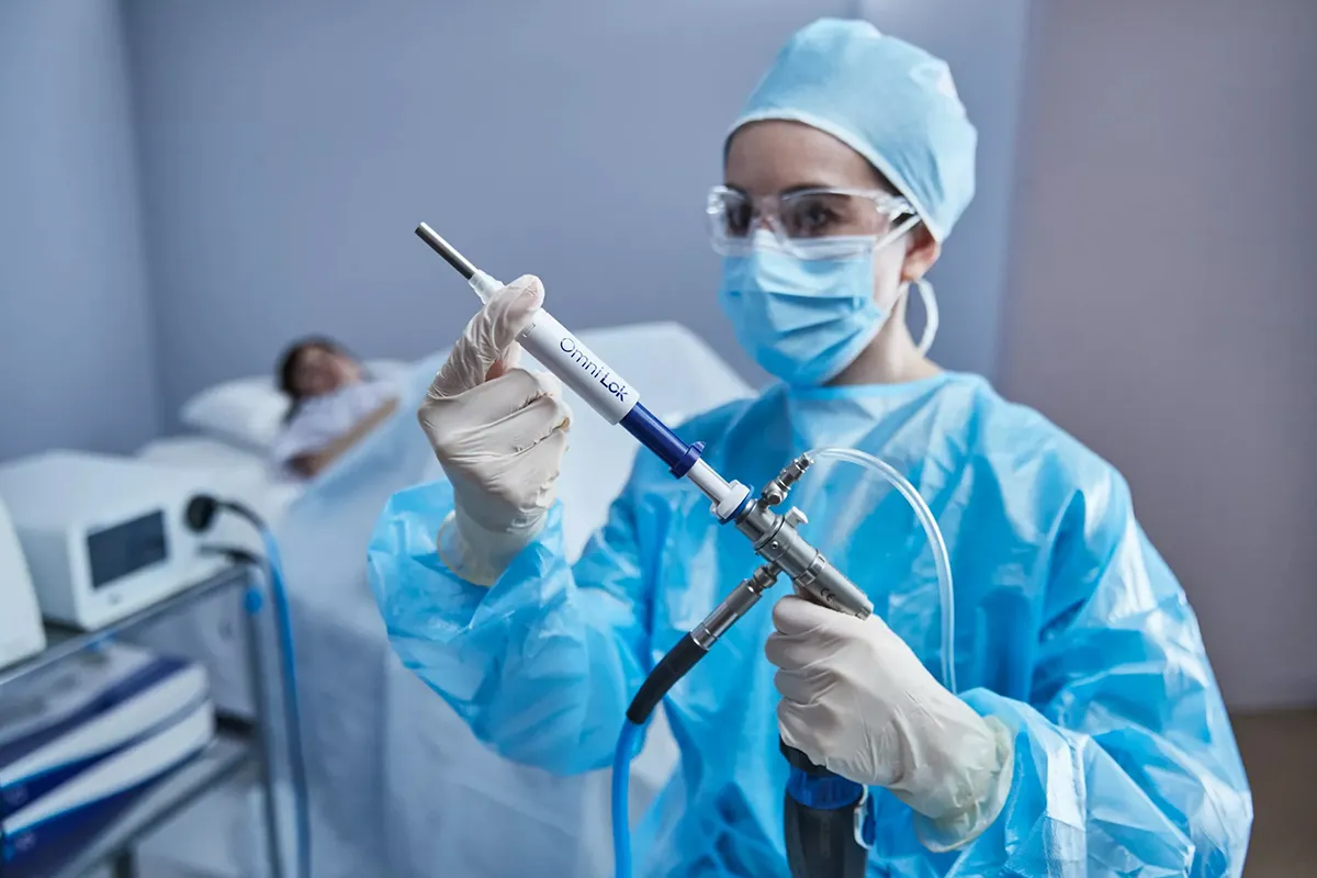 Prestador de cuidados de saúde segurando um histeroscópio Omni® e o selo em frente a uma doente.