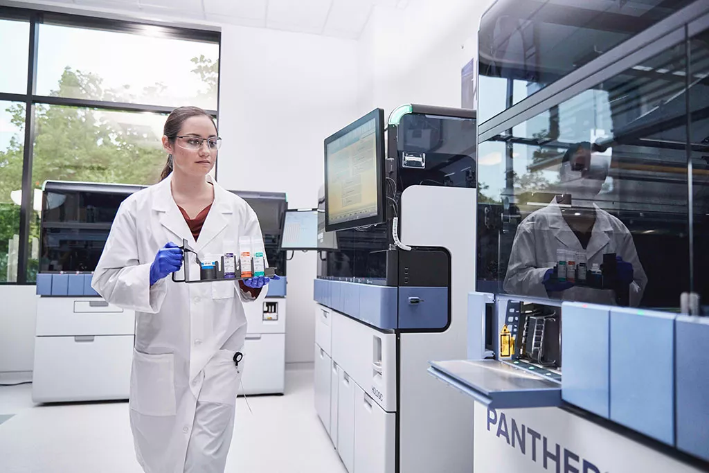 Técnica de laboratório a segurar um tabuleiro de amostras para colocar no sistema Panther