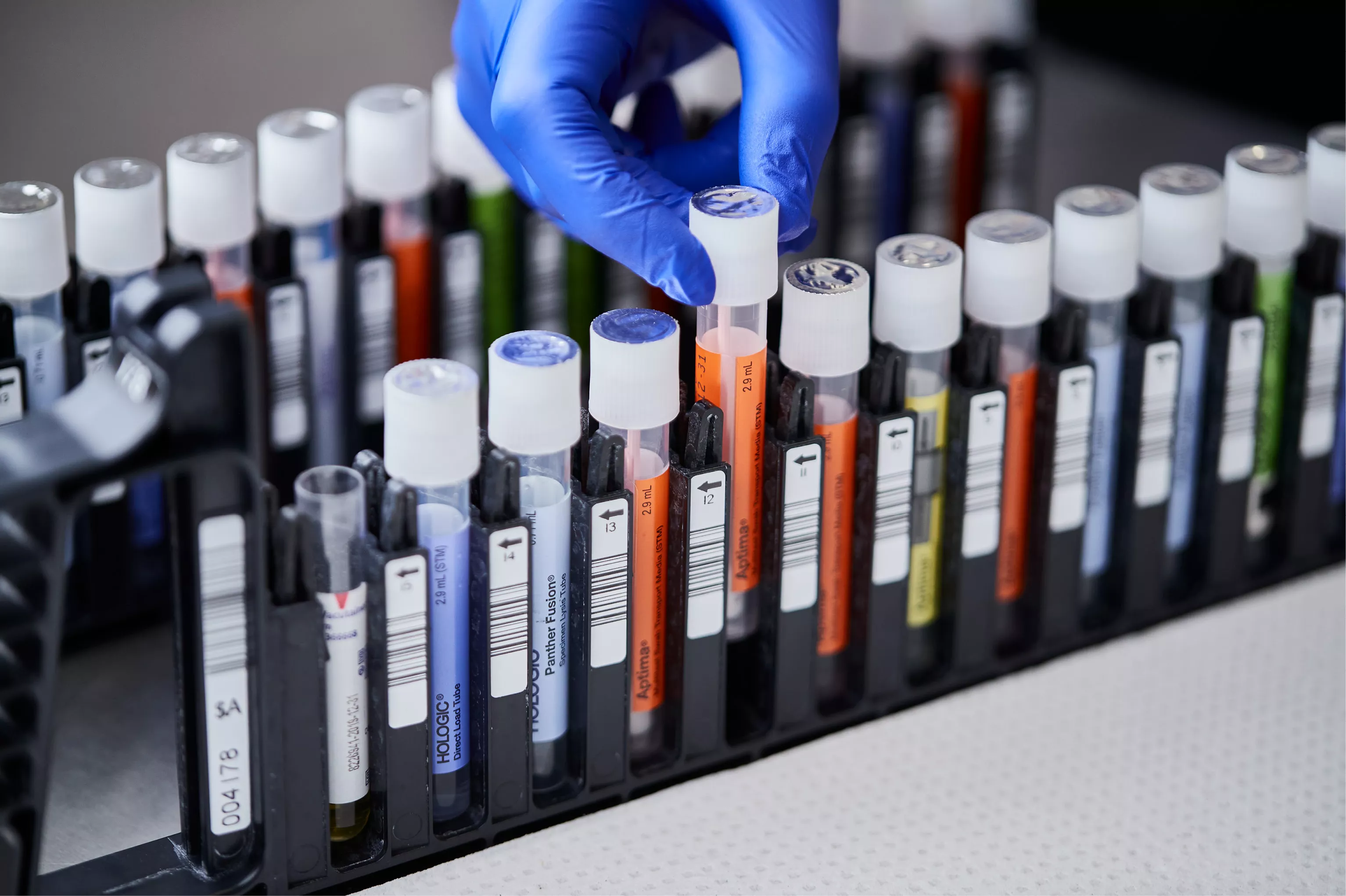 Pessoa a usar luva a tirar um frasco do tabuleiro