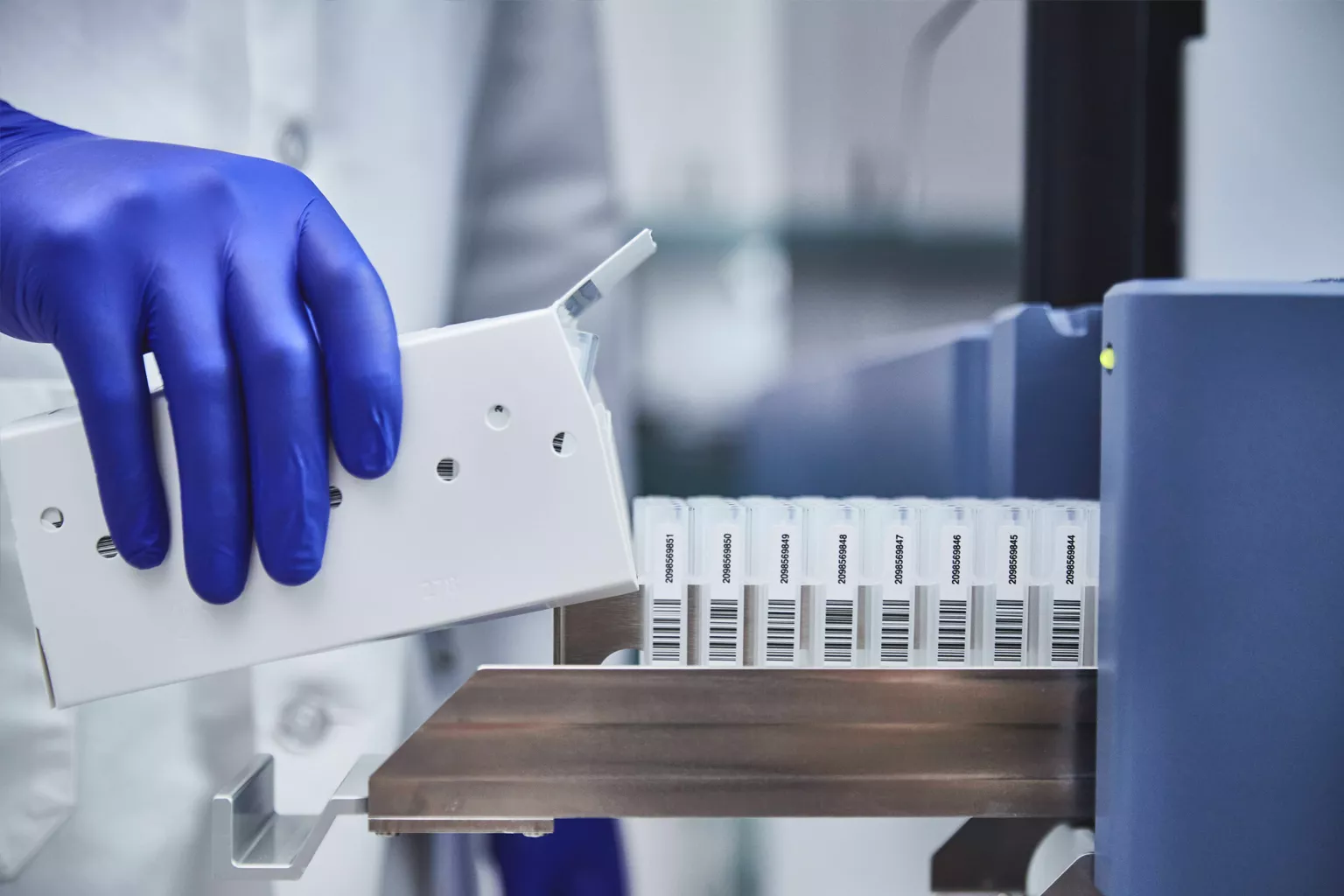 Técnico de laboratório enche tubos num tabuleiro.